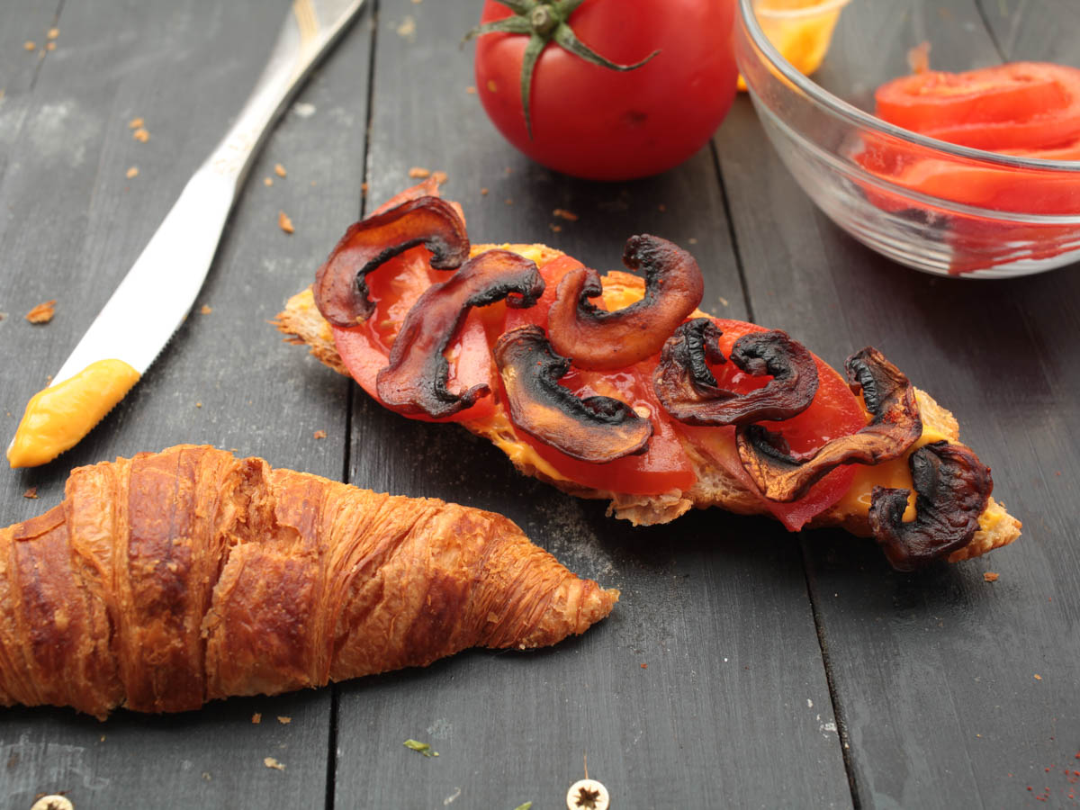 vegan mushroom bacon in croissant sandwich
